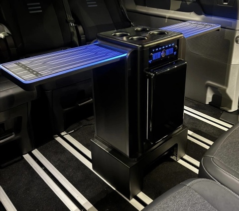 BOX TABLE rozłożony w Fordzie Tourneo Custom z niebieskim podświetleniem LED i napojami na blacie.